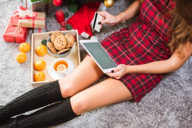 Tablet ile kredi kartı yerde yatarken ve boşluk tutan kadın. Noel alışveriş kavramı