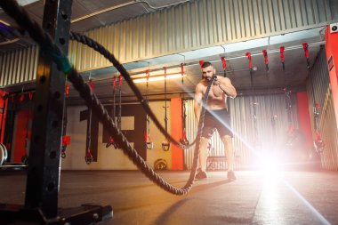 Genç adam birlikte savaş ipler fitness salonunda egzersiz yerleştirmek