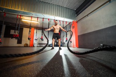 Genç adam birlikte savaş ipler fitness salonunda egzersiz yerleştirmek