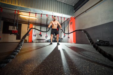 Genç adam birlikte savaş ipler fitness salonunda egzersiz yerleştirmek