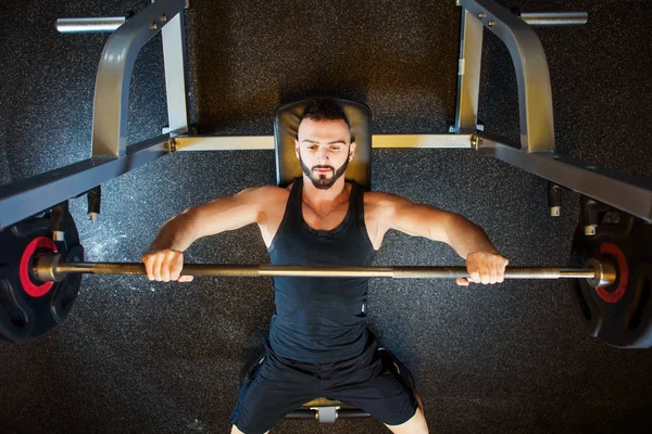 Mladý muž v tělocvičně cvičení hrudníku na Bench pressu — Stock fotografie