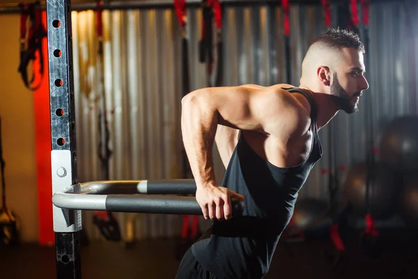 Muskulöser Mann trainiert im Fitnessstudio und macht Übungen am parallelen Barren — Stockfoto