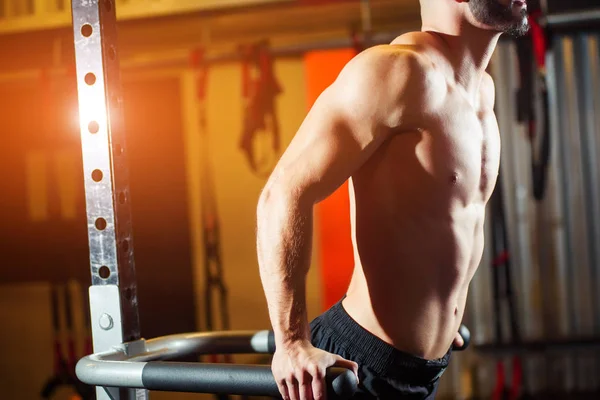 Homem musculoso trabalhando no ginásio fazendo exercícios em barras paralelas — Fotografia de Stock