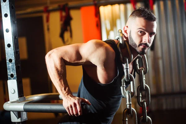 Homem musculoso trabalhando no ginásio fazendo exercícios em barras paralelas — Fotografia de Stock