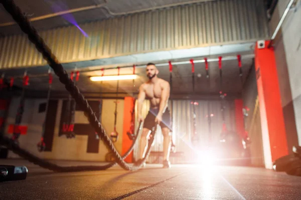 Jovem homem apto a se exercitar com cordas de batalha no ginásio de fitness — Fotografia de Stock
