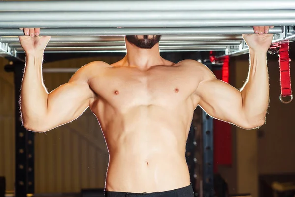 Atleta muscular ajuste homem puxando para cima no horizontal bar no um ginásio — Fotografia de Stock