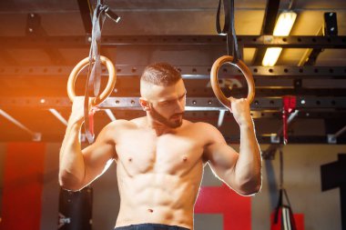 Genç kaslı adamla çıplak gövde üzerinde jimnastik egzersizleri yapıyor