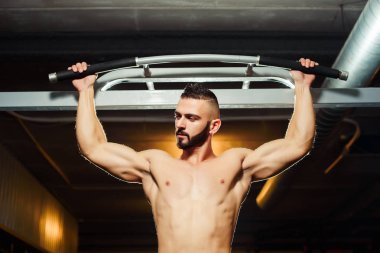 Bir spor salonunda yatay çubuğu yukarı çekerek uygun atlet kaslı adam