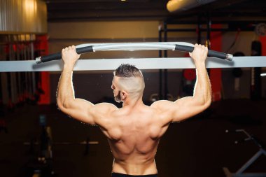 Bir spor salonunda yatay çubuğu yukarı çekerek uygun atlet kaslı adam