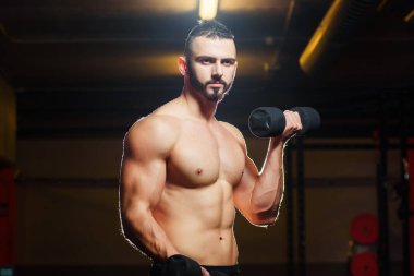Spor salonunda dumbbells ile çalışma dışarı kas gömleksiz genç adam