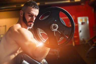 Barbell ile eğitim ve pazı arayan genç kaslı adam 