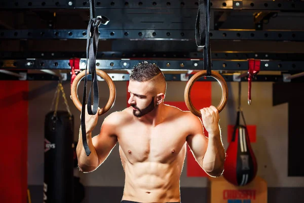 Svalnatý mladík s nahý trup dělá cvičení na gymnastických — Stock fotografie