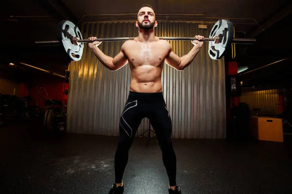 Homem musculoso treinando agachamentos com sinos no ginásio — Fotografia de Stock