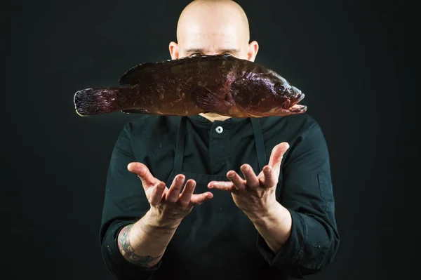 Chef throwing a big fish into the air on black background — Stock Photo, Image