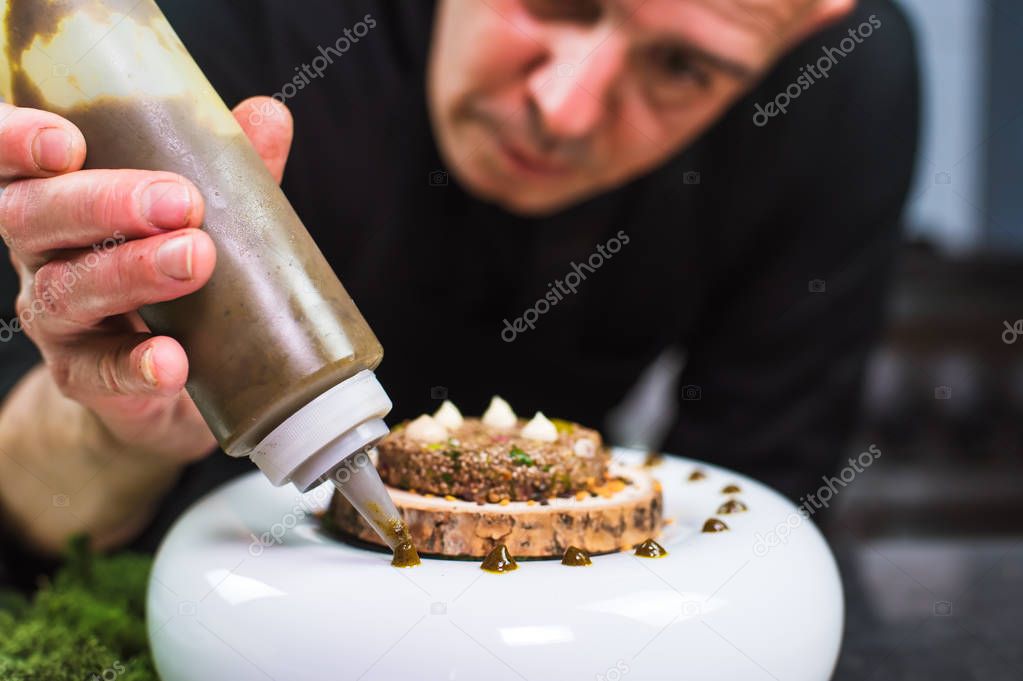 Young chef preparing modern molecular dish with sauce