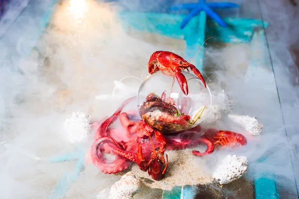 Molecular modern cuisine dish of octopus and crab placed in glass and covered with nitrogen smoke