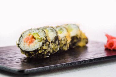 Rulo ve suşi siyah bir taş plaka üzerinde