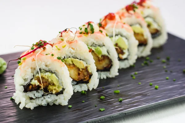 Rollos tradicionales japoneses y sushi en un plato de piedra negra — Foto de Stock