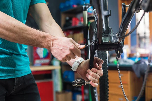 Closeup of male masters' hands repairing the chain mechanism of the bicycle in a special store