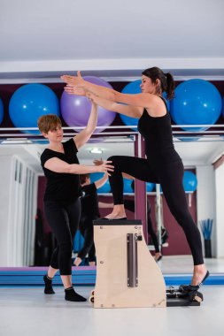 Genç kadın üzerinde açılan wunda egzersiz pilates ile kişisel eğitmen sandalye. Fitness yoga spor salonunda egzersiz. Sağlıklı ve aktif yaşam tarzı