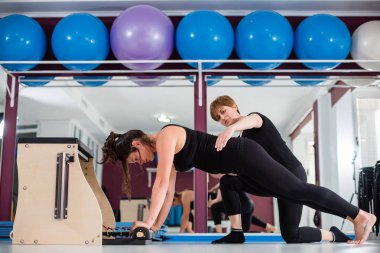 Genç kadın üzerinde açılan wunda egzersiz pilates ile kişisel eğitmen sandalye. Fitness yoga spor salonunda egzersiz. Sağlıklı ve aktif yaşam tarzı