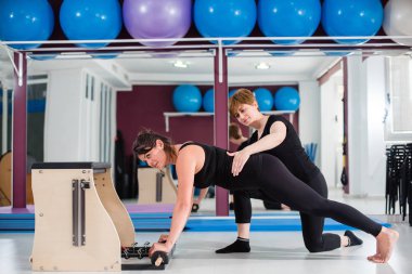 Kişisel eğitmen denetleyici genç kadın üzerinde açılan wunda egzersiz pilates ile kişisel eğitmen sandalye. Fitness yoga spor salonunda egzersiz. Sağlıklı ve aktif yaşam tarzı