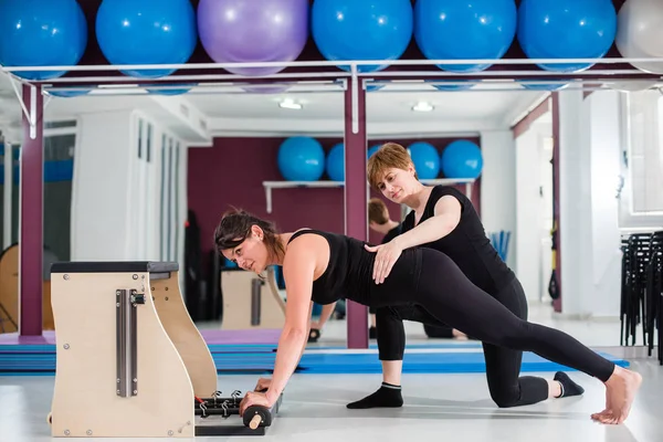 Kişisel eğitmen denetleyici genç kadın üzerinde açılan wunda egzersiz pilates ile kişisel eğitmen sandalye. Fitness yoga spor salonunda egzersiz. Sağlıklı ve aktif yaşam tarzı