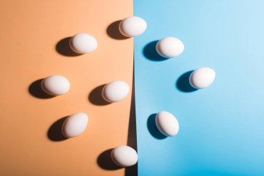 Mavi ve bej renkli arka plan üzerinde beyaz Paskalya yumurtaları