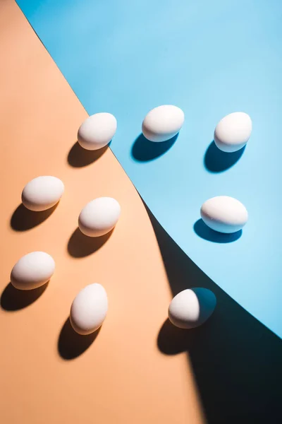 Huevos blancos de Pascua sobre fondo azul y beige — Foto de Stock