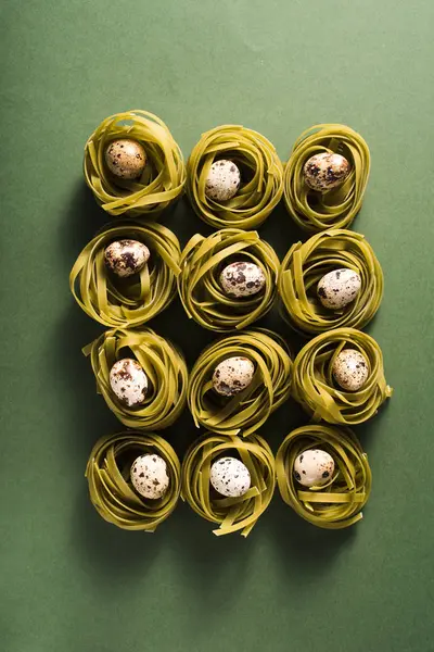 Huevos de codorniz en los nidos de pasta de espinacas sobre fondo verde — Foto de Stock
