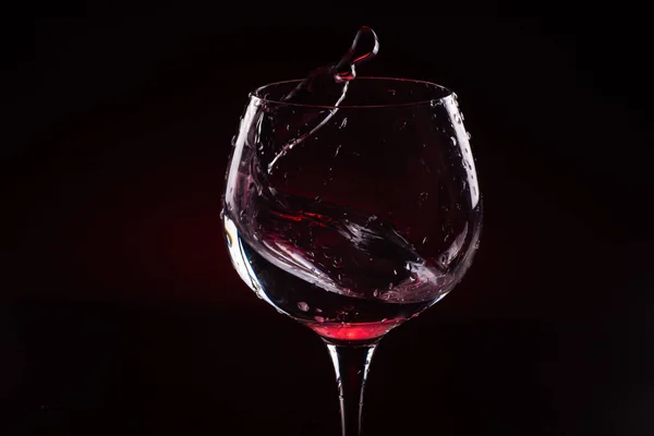 Rotwein spritzt aus einem hohen Weinglas — Stockfoto
