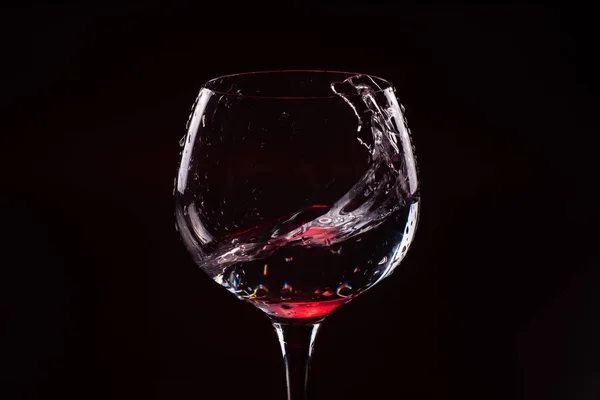 Vino tinto salpicando de una copa de vino alta — Foto de Stock