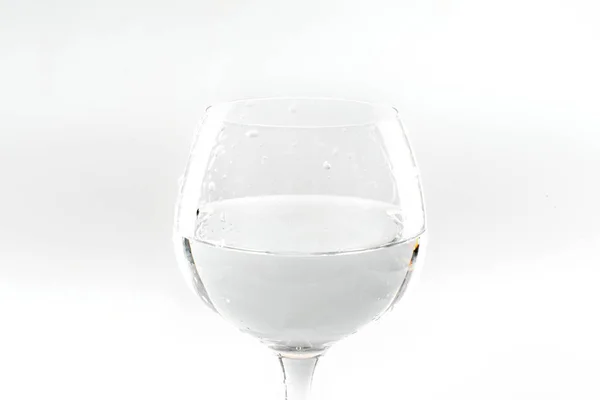 Kieliszek do wina częściowo wypełnione wodą na białym tle — Zdjęcie stockowe
