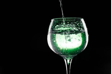 Yeşil arka plana sahip şarap cam su dökme