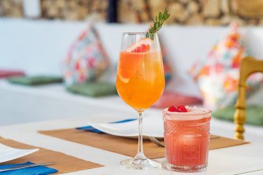 Close-up glasses of grapefruit and raspberry cocktails at bar background.