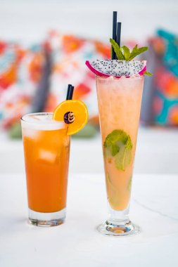 Close-up of orange alcoholic cocktails in tall glass on white table.