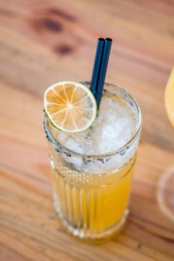 Top view of an orange cocktail in a tall glass on wooden background.