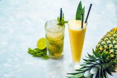 Beyaz bir masada pinina colada ve mojito alkollü kokteyller..