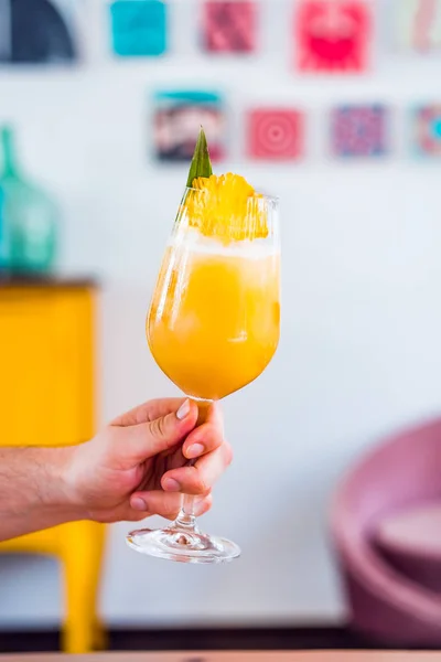 Close-up van mannelijke handen met sinaasappel vers fruit cocktail drankje met ananas. — Stockfoto