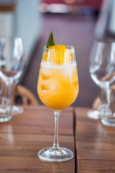 Oranje fris fruit cocktail drankje met ananas in een hoog glas aan bar achtergrond. — Stockfoto