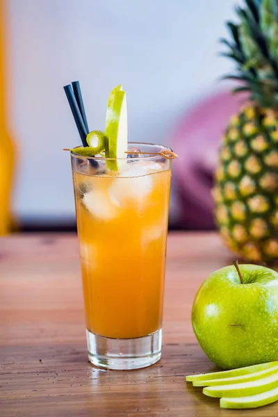 Close-up van een cocktail van sinaasappel en vers fruit in een hoog glas met appelversiering. — Stockfoto