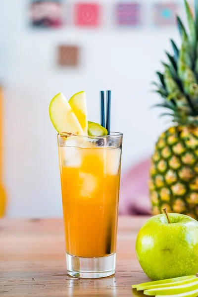 Close-up van een cocktail van sinaasappel en vers fruit in een hoog glas met appelversiering. — Stockfoto