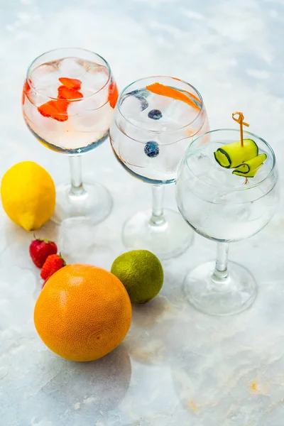 Top visning af tre gin tonic cocktails med jordbær, kalk og blåbær . - Stock-foto