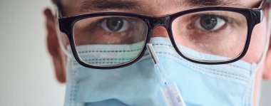 Gözlüklü, tıbbi maskeli ve termometreyi elinde tutan tek kullanımlık eldivenli genç adamın yakın plan portresi. Coronavirus, Covid-19, 2019-NCoV salgını. Boşluğu kopyala.
