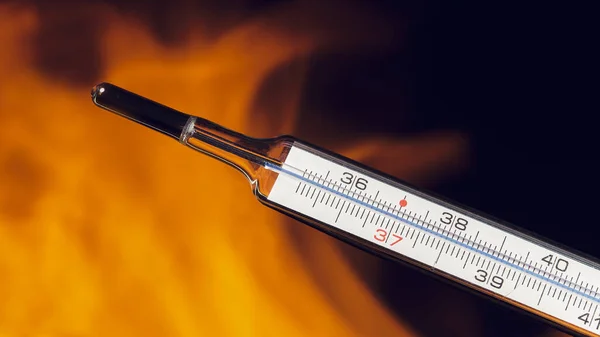 Close-up of mercury thermometer in fire. Thermometer against the flame. Copy space.