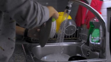 Kadın elleri evdeki mutfak lavabosunda bulaşık yıkıyor ve duruluyor. Bulaşık yıkama, ev işleri..