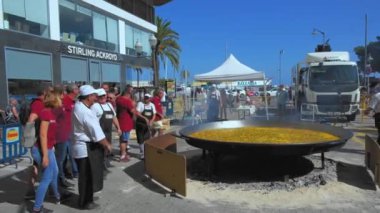 DENIA, SPAIN - Haziran 2019: Bir adam geleneksel paella valenciana pişirme sürecidir tavada et kızartmak için pirinç yapılır.