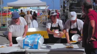 Denia, İspanya - Temmuz 2019. Aşçılar geleneksel Valensiyalı pirinç paellasını tatmak için sofraya koydular.