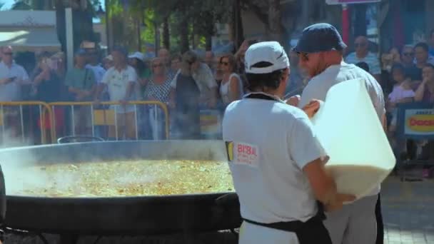 Denia, Španělsko - červenec2019. Detailní záběr. Muž vaří rýži a vaří tradiční paellu z Valencie z rýže na pánvi.