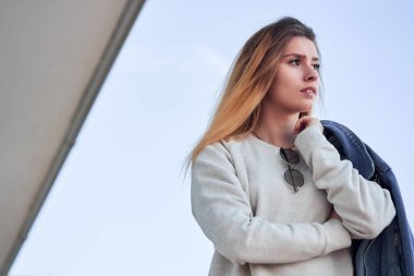 Güzel, karizmatik bir kız, açık renk kazaklı, v kot ceketli, uzun sarı saçlı yaz gününde.